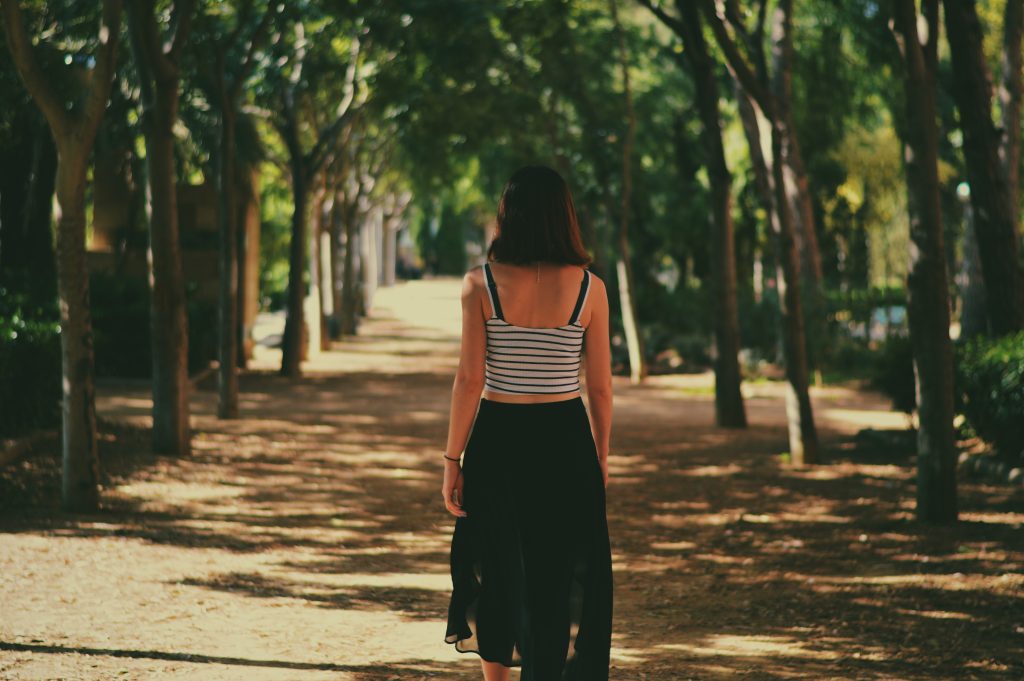 Người phụ nữ đi bộ trên con đường mòn giữa thiên nhiên