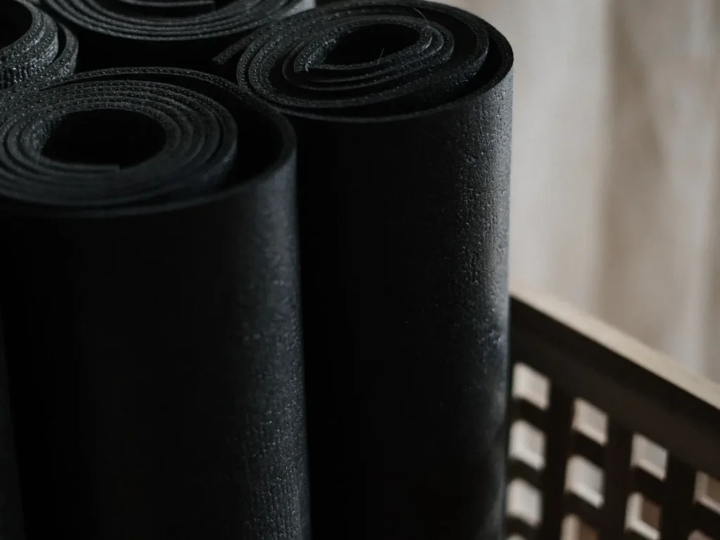 Những tấm thảm yoga màu đen cuộn tròn xếp trong giỏ gỗ